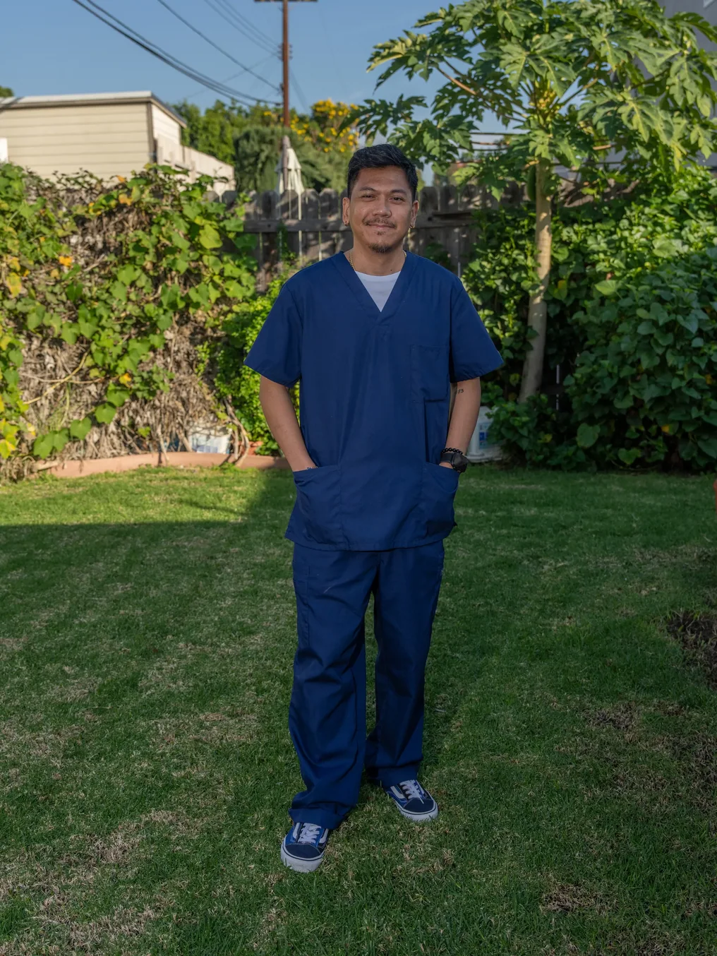 Caregiver in navy scrubs standing in home garden setting
