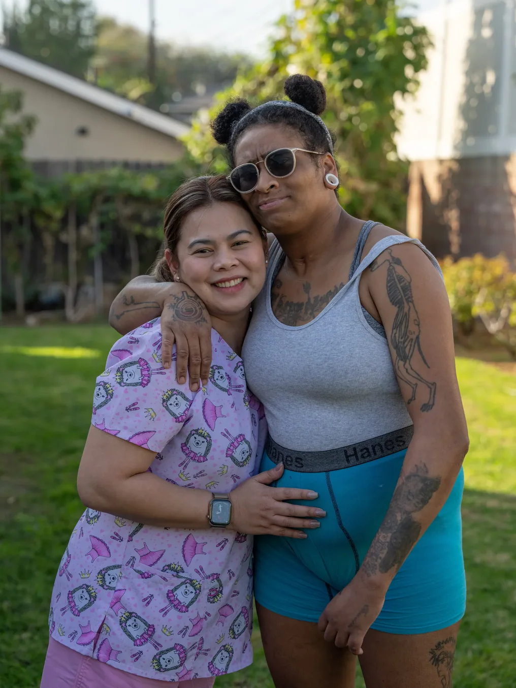 Two caregivers or family members embracing in a sunny residential care facility yard